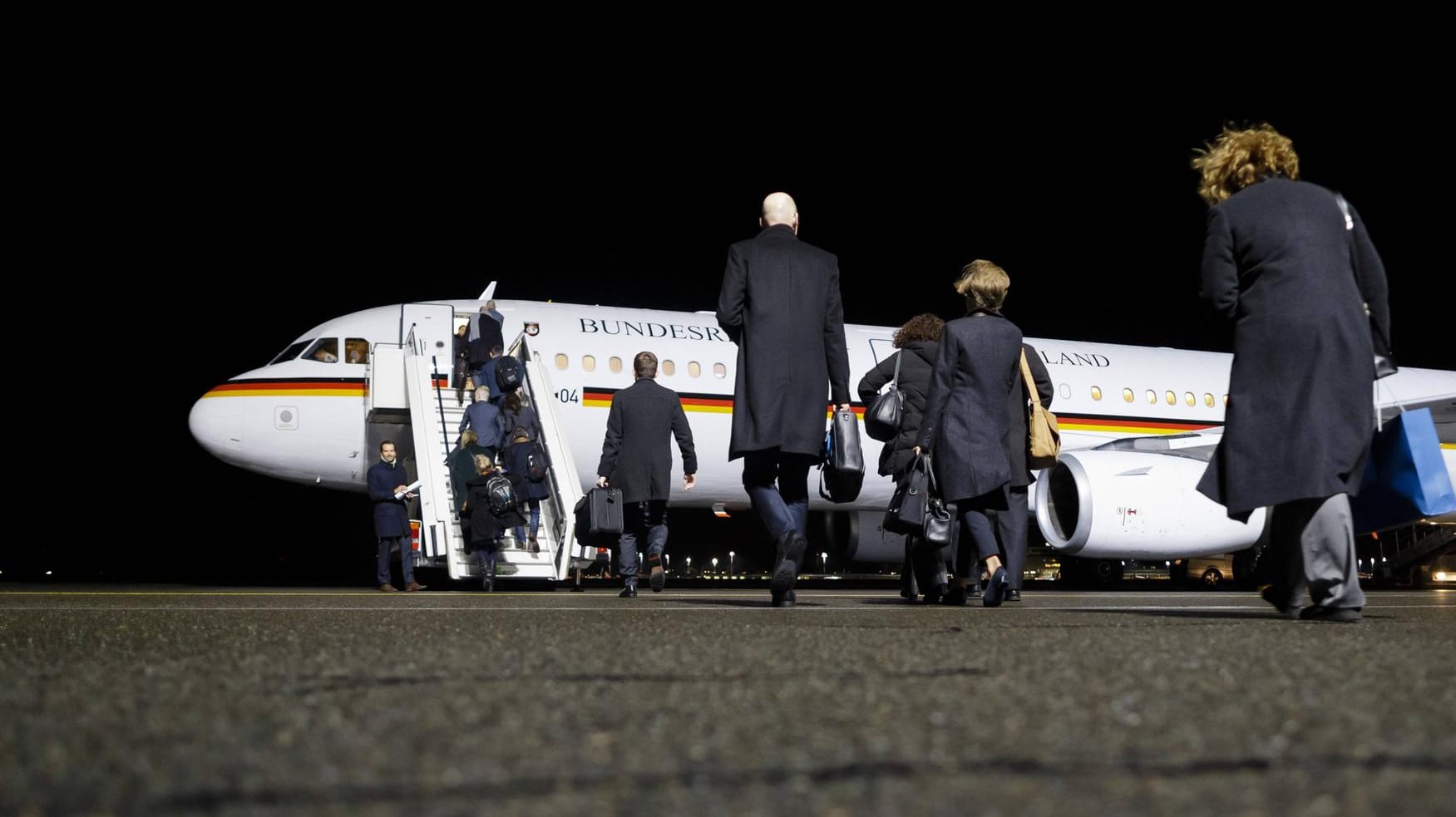 Mitglieder einer Delegation: Sie gehen über das Flugfeld zu einer deutschen Regierungsmaschine.