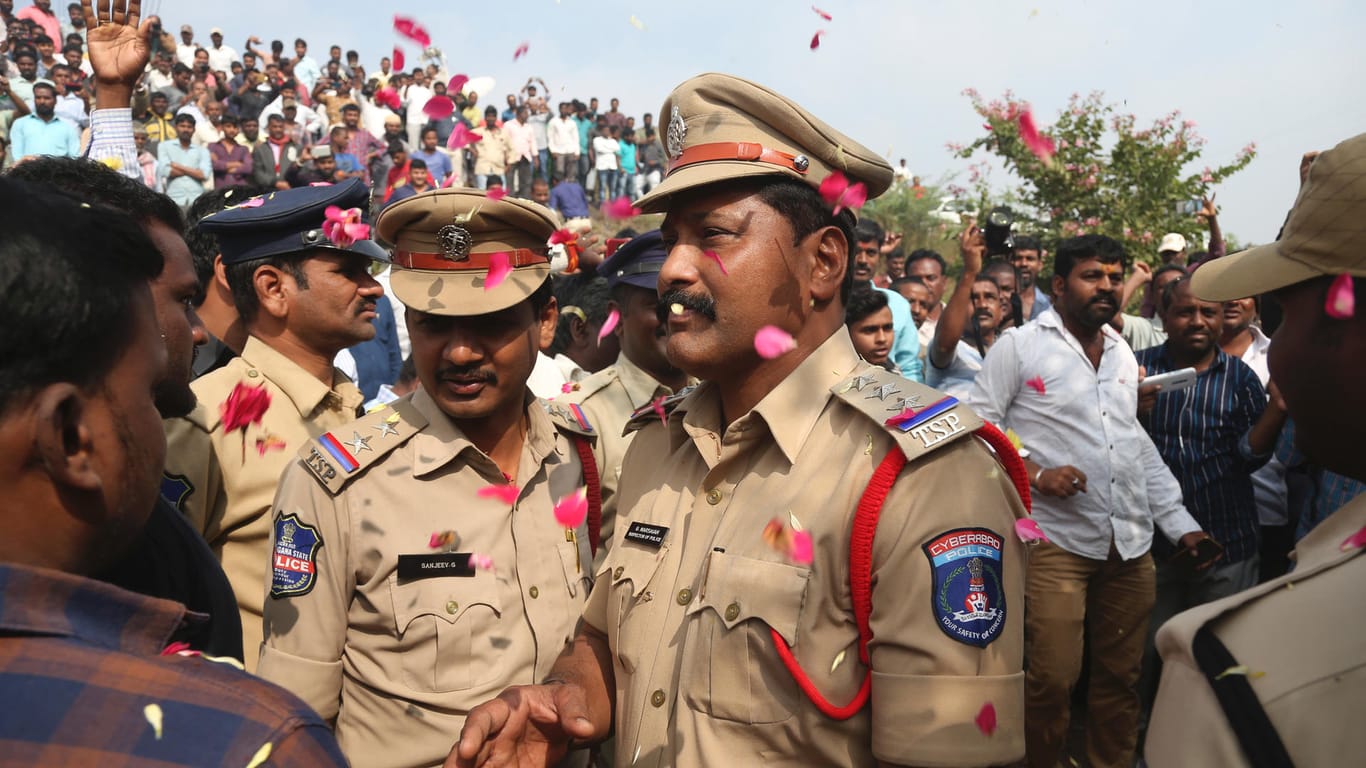 Menschen werfen Blütenblätter auf indische Polizisten: Die Beamten haben vier Verdächtige erschossen.