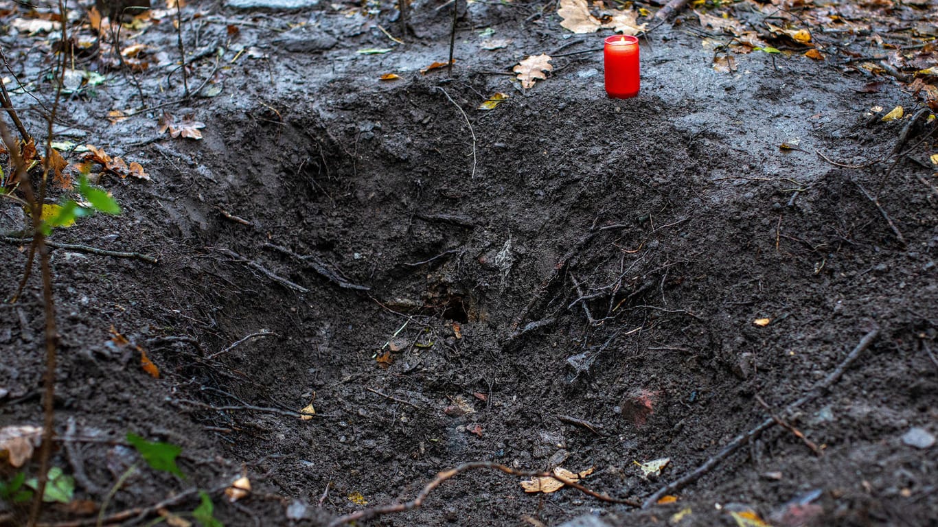 Ein Grablicht steht an einem Loch in einem Waldstück bei Duisburg: Die Polizei hatte hier die Leiche einer jungen Frau gefunden.