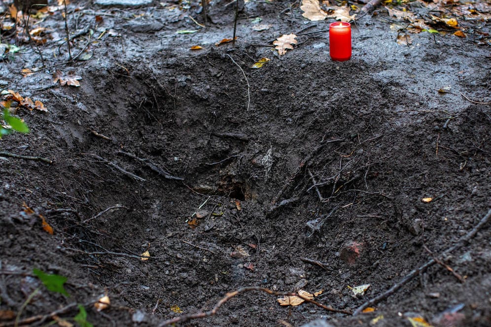 Ein Grablicht steht an einem Loch in einem Waldstück bei Duisburg: Die Polizei hatte hier die Leiche einer jungen Frau gefunden.