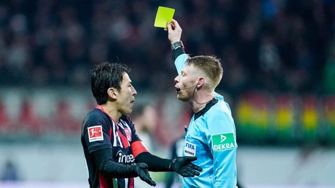Eintracht-Coach Hütter kritisiert die Leistung des Schiedsrichters: Christian Dingert (r) zeigt Frankfurts Makoto Hasebe (l) gelb.