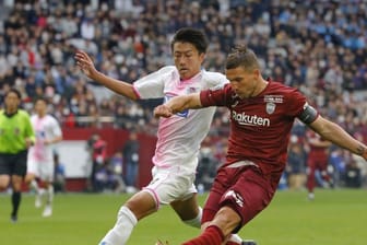 Lukas Podolski (r) im Duell um den Ball mit einem Gegenspieler.