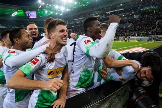Die Gladbacher Spieler jubeln nach dem Treffer zum 2:1 durch Ramy Bensebaini (r).