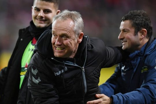 Freiburgs Trainer Christian Streich (M) bejueblt den 1:0-Sieg über den VfL Wolfsburg mit Torwarttrainer Andreas Kronenberg (r).