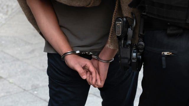 Polizisten führen nach einer Razzia einen verdächtigen Mann ab.