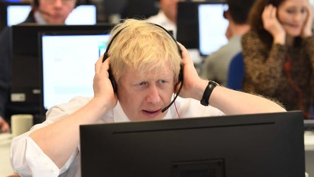 Großbritanniens Premierminister Boris Johnson sitzt mit anderen Kabinettsmitgliedern mit Headset vor einem Bildschirm an einem Tisch im Call Center des Hauptquartiers der Konservativen während des Wahlkampfs.