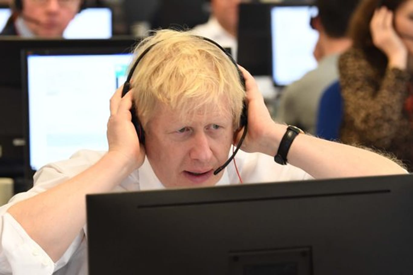 Großbritanniens Premierminister Boris Johnson sitzt mit anderen Kabinettsmitgliedern mit Headset vor einem Bildschirm an einem Tisch im Call Center des Hauptquartiers der Konservativen während des Wahlkampfs.
