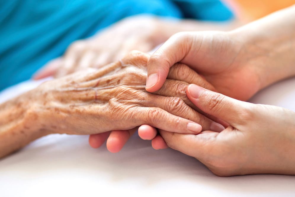 Angehörige hält alter Frau die Hand: In einer Patientenverfügung legen Menschen fest, welche ärztliche Behandlung sie einfordern oder ablehnen.