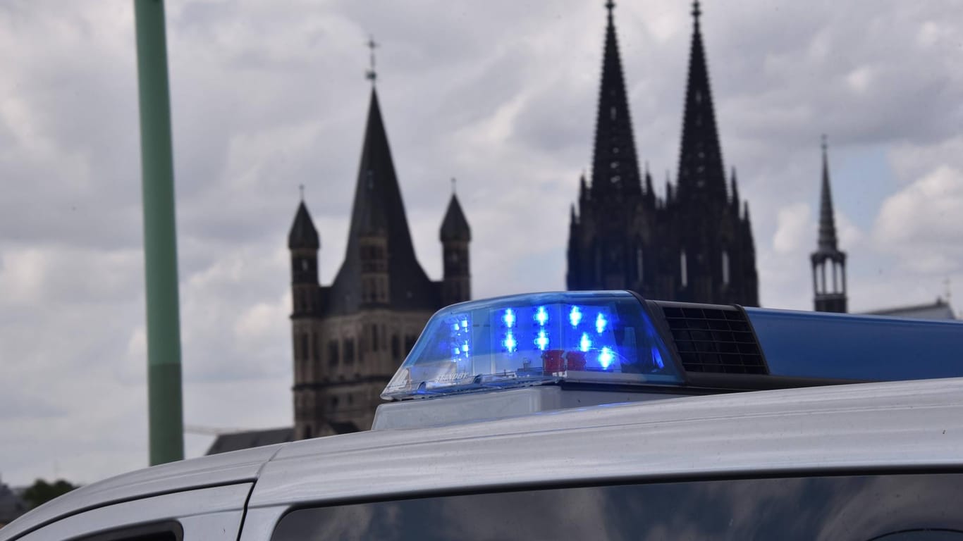 Blaulicht an einem Polizeiwagen vor Kölner Dom: Ein Beamter ist in der Domstadt von einem 23-Jährigen schwer verletzt worden.