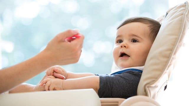 Baby wird gefüttert: Sobald sich Kinder für das Essen von Mama oder Papa interessieren, können Eltern den Beikost-Start versuchen.