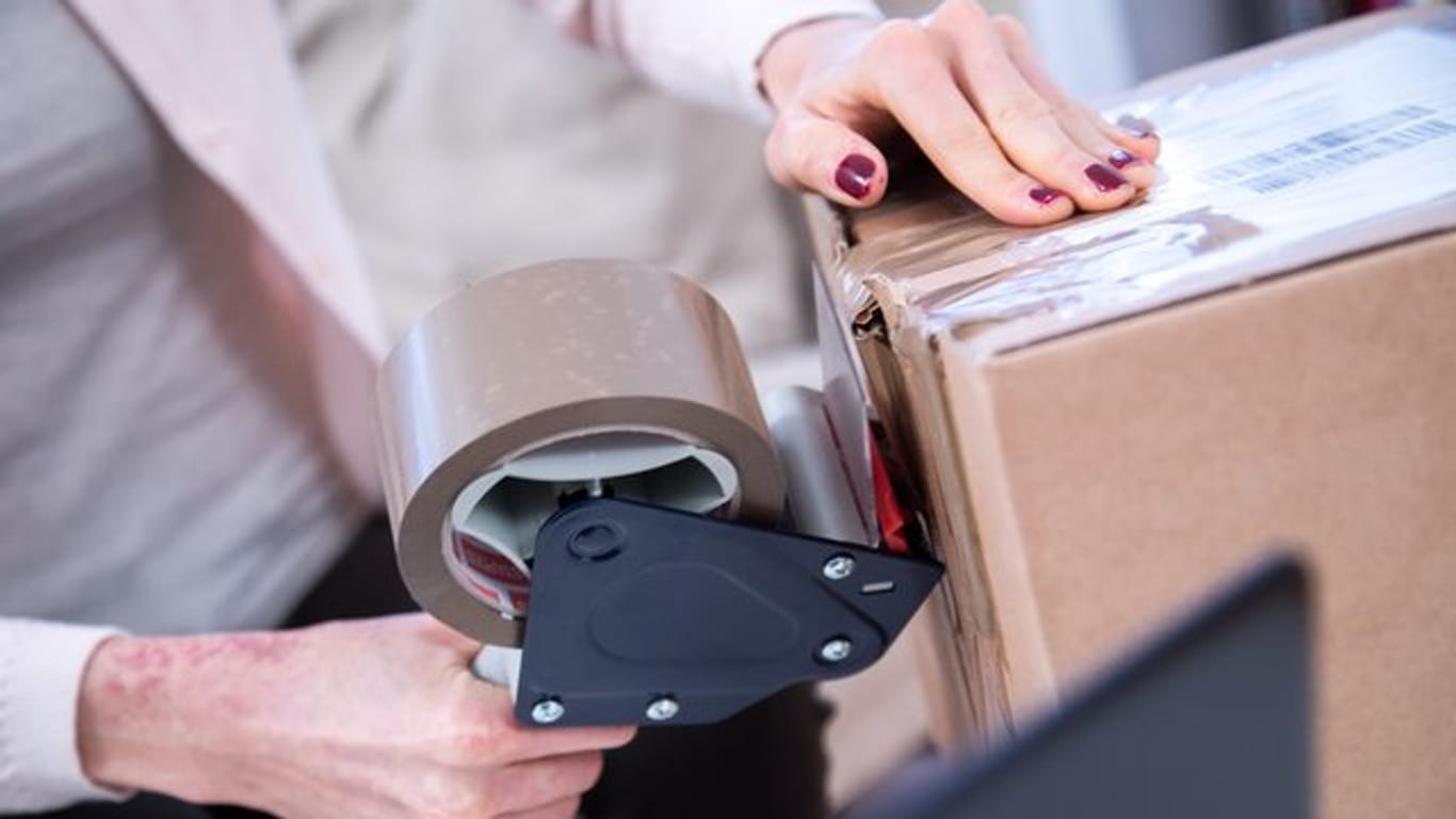 Eine Frau verpackt ein Paket: Forscher mahnen zu Rücksendegebühren im Onlinehandel.