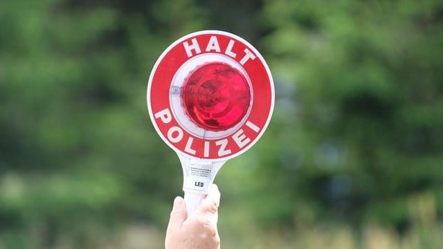 Eine Polizistin hält eine Winkerkelle in die Höhe