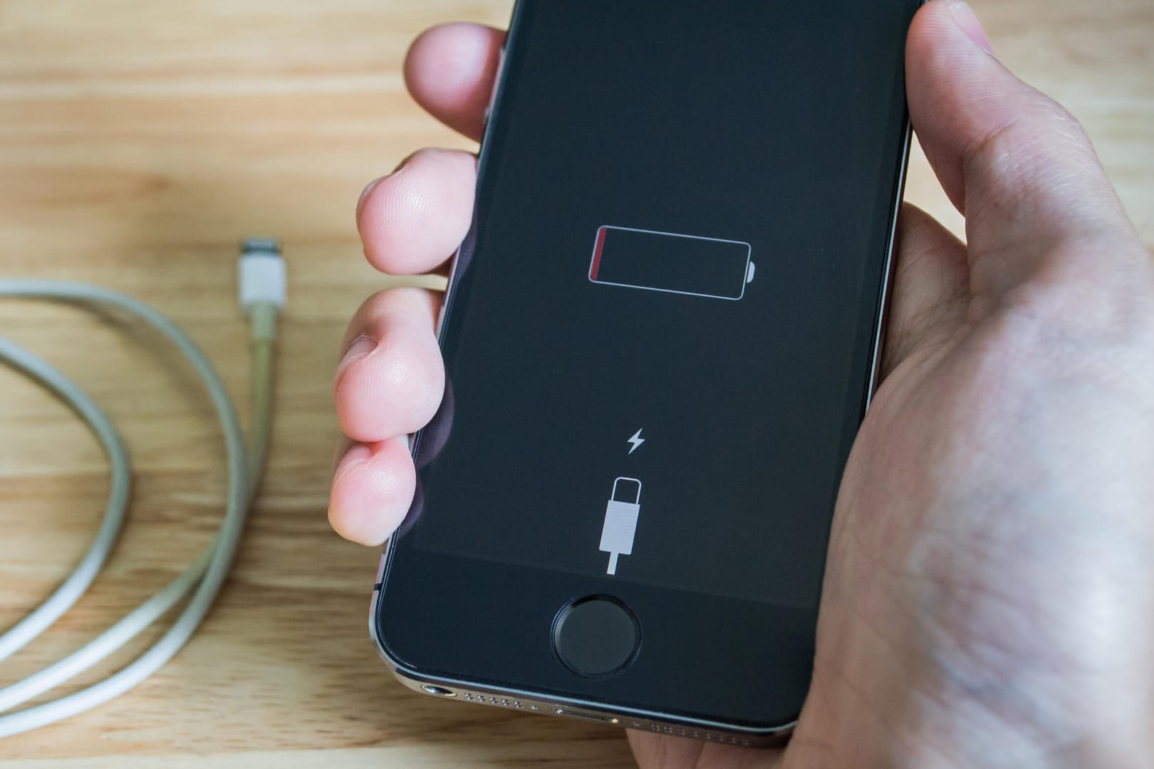 Ein Nutzer hält ein iPhone, dessen Akku fast leer ist: Wenn das Smartphone zu viel Energie verbraucht, kann das verschiedene Gründe haben.