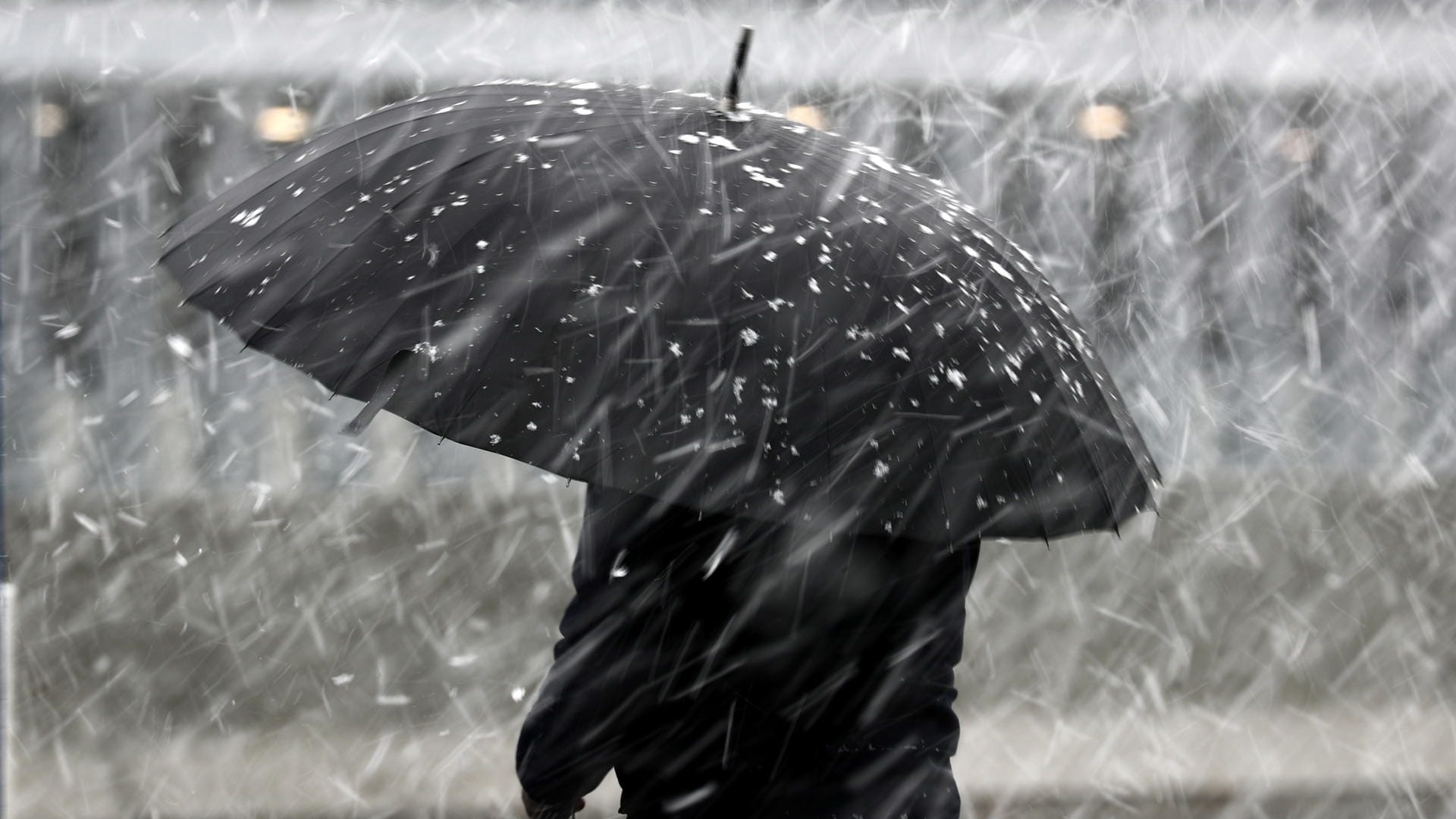 Eine Frau mit Regenschirm im Schneeregen: Bis zu 4 Zentimeter Schnee könnten am Mittwoch noch fallen. (Symbolbild)