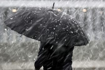 Eine Frau mit Regenschirm im Schneeregen: Bis zu 4 Zentimeter Schnee könnten am Mittwoch noch fallen. (Symbolbild)