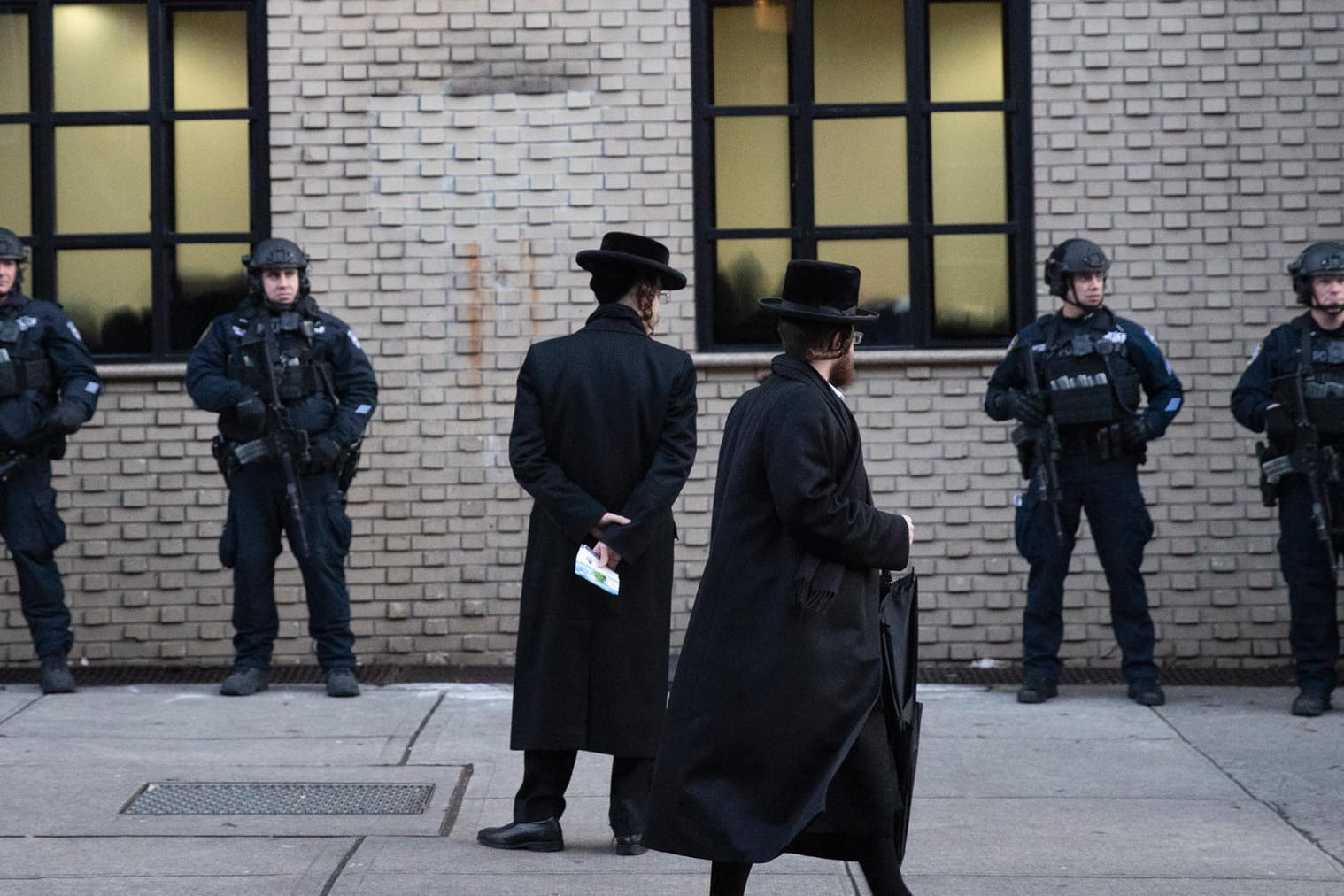 Orthodoxe jüdische Männer gehen an Polizisten vorbei, die eine Synagoge bewachen: Noch wollte die Polizei kein antisemitisches Motiv bestätigen.