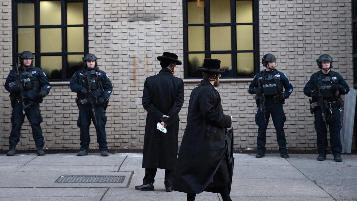 Orthodoxe jüdische Männer gehen an Polizisten vorbei, die eine Synagoge bewachen: Noch wollte die Polizei kein antisemitisches Motiv bestätigen.