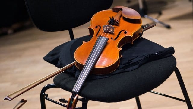 Eine Geige liegt in einer Probenpause im Konzertsaal der Philharmonie Bad Reichenhall auf einem Stuhl. Eine Geige liegt in einer Probenpause im Konzertsaal der Philharmonie Bad Reichenhall auf einem Stuhl.