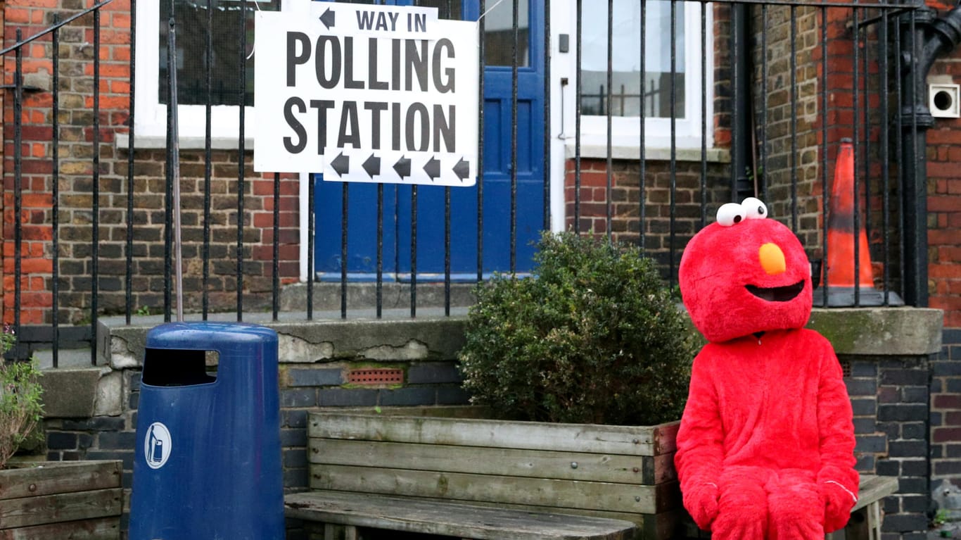 Eine als Elmo verkleidete Frau vor einem Wahlbüro.
