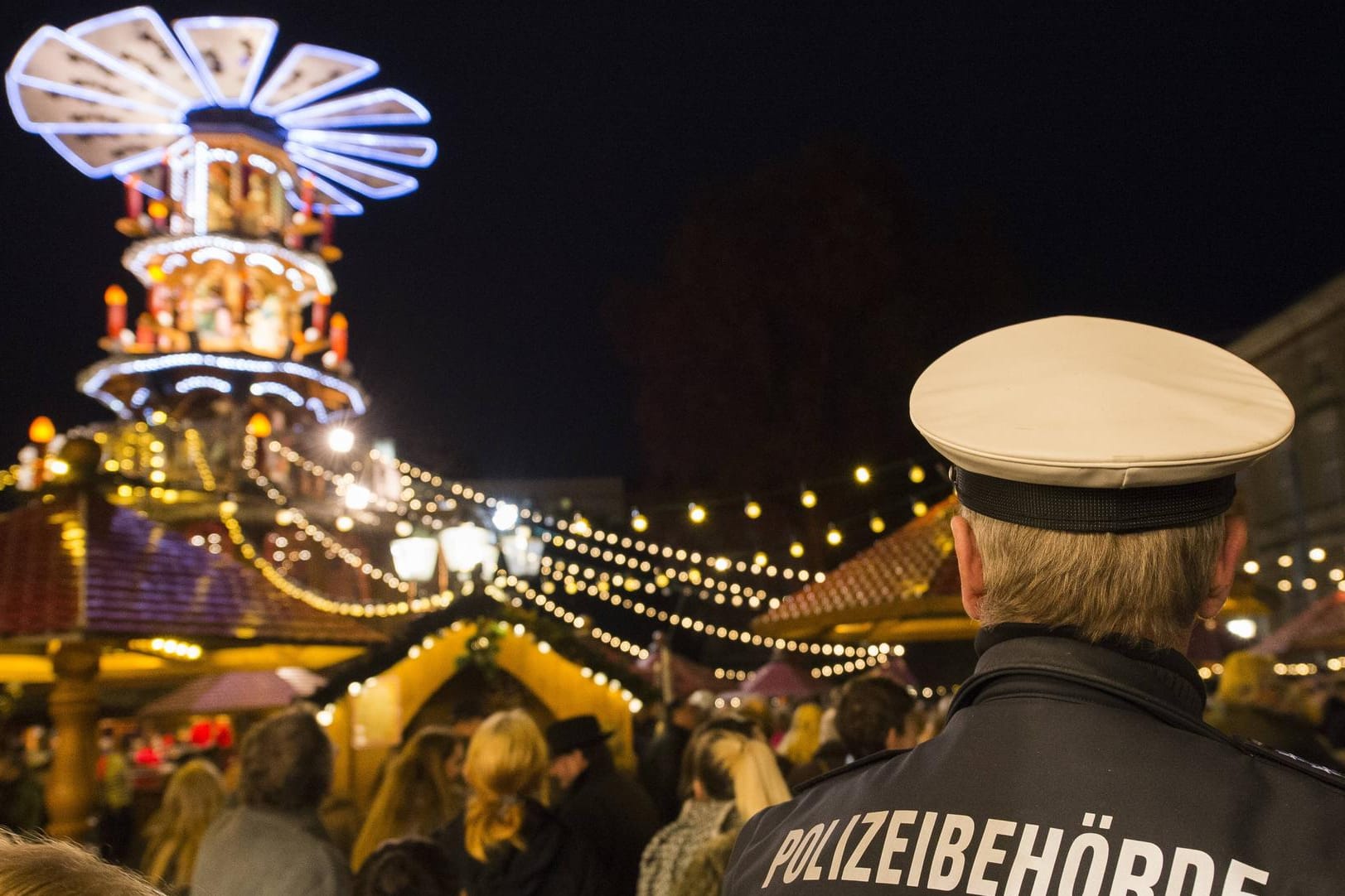 "Polizeibehörde" steht auf dem Rücken eines Uniformierten auf dem Karlsruher Weihnachtsmarkt (Symbolbild): Die Polizei ging hier einem Hinweis einer ausländischen Behörde nach.