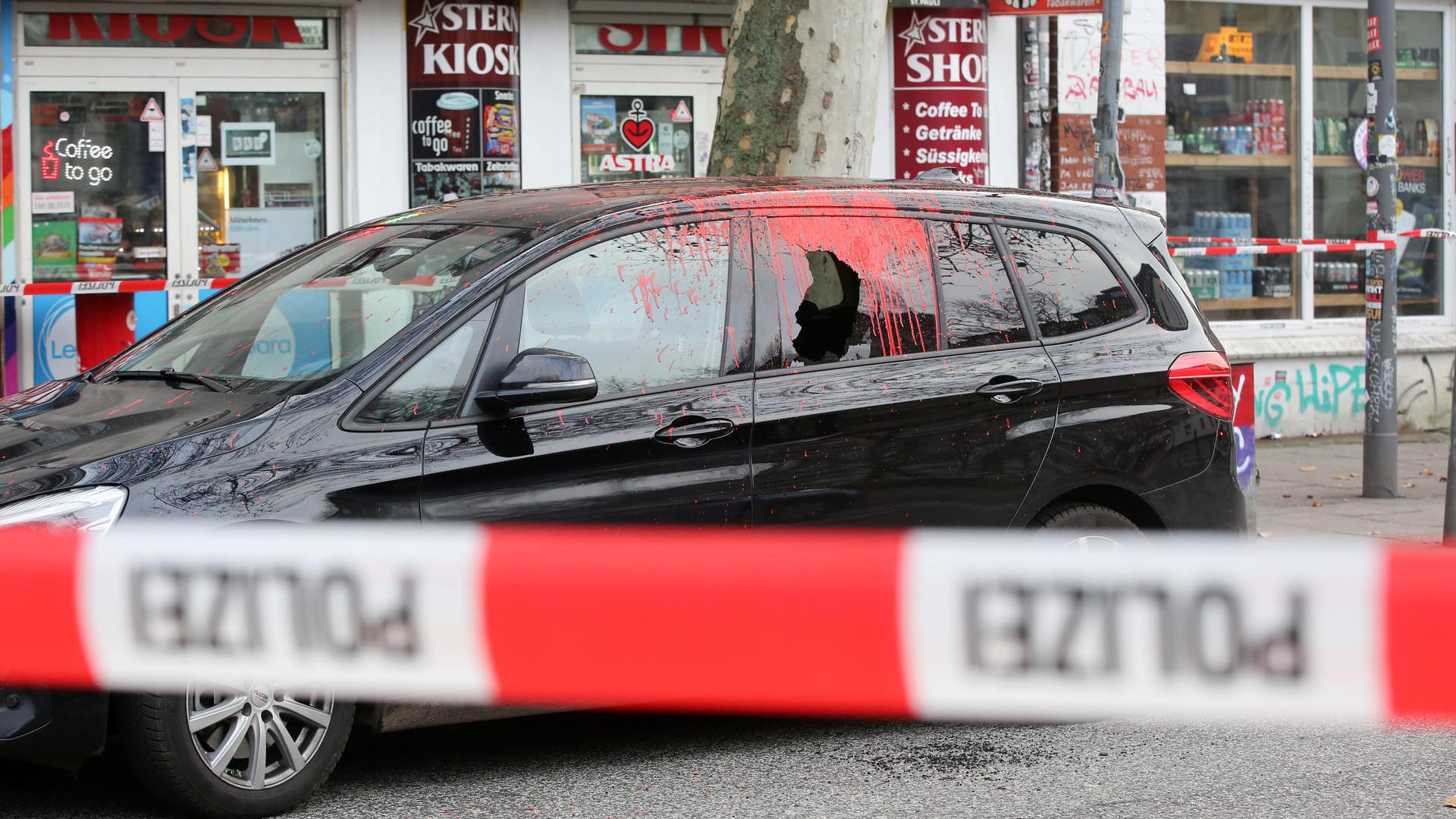 Ein beschädigtes Fahrzeug steht hinter einer Polizeiabsperrung: Die Attacke der Unbekannten traf auch andere Autos.