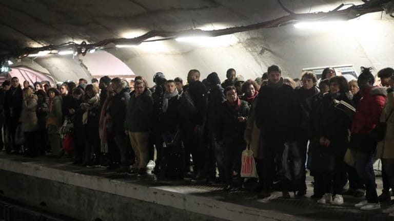 Pendler warten an einem Bahnsteig in Paris vergeblich auf eine U-Bahn.