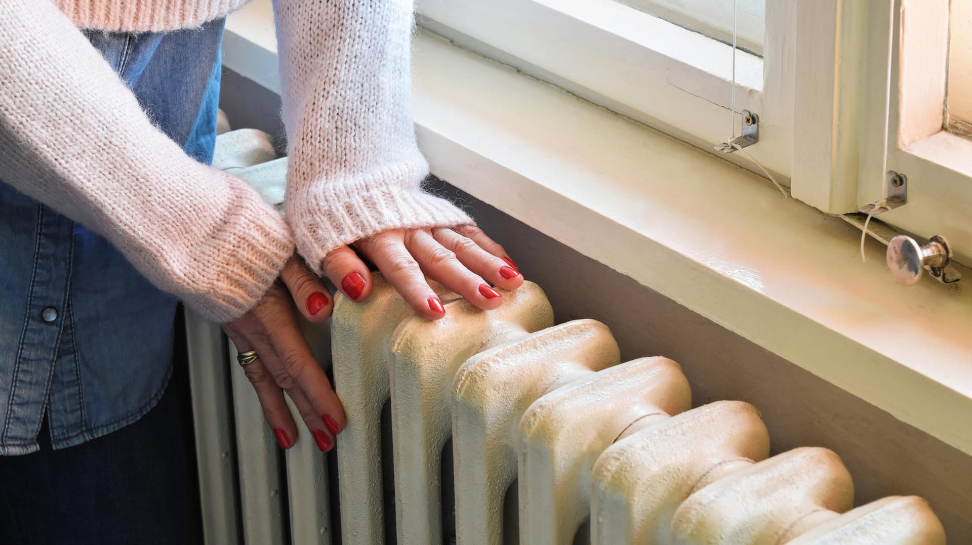 Frau greift an die Heizung: Forscher haben herausgefunden, dass die Raumtemperatur nicht nur eine Frage des Wohlfühlfaktors ist, sondern auch über die Leistungsfähigkeit entscheiden kann.