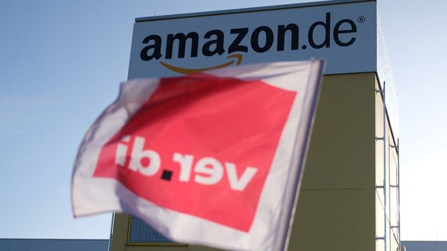 Eine Fahne von Verdi hängt an dem Zaun eines Logistikzentrums von Amazon: Bei Amazon wird seit Mai 2013 in Deutschland immer wieder gestreikt – ohne dass es zu konkreten Ergebnissen kommt.
