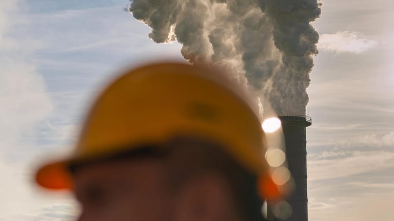 Arbeiter mit Schutzhelm vor den Abluftfahnen des Heizkraftwerks Moorburg bei Hamburg: Der Preis für eine Tonne CO2 soll von zehn auf 25 Euro steigen. (Symbolfoto)