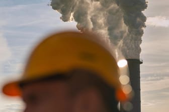 Arbeiter mit Schutzhelm vor den Abluftfahnen des Heizkraftwerks Moorburg bei Hamburg: Der Preis für eine Tonne CO2 soll von zehn auf 25 Euro steigen. (Symbolfoto)