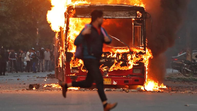 Mann rennt vor brennendem Bus in Neu Delhi über die Straße: Die Proteste richten sich gegen ein diskriminierendes Staatsbürgerschaftsgesetz.