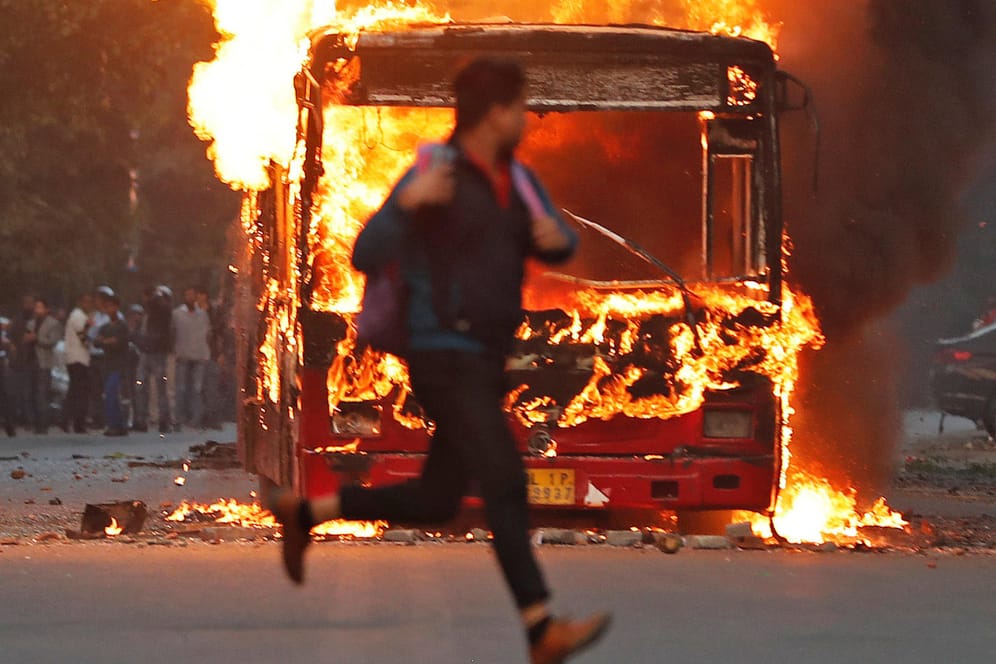 Mann rennt vor brennendem Bus in Neu Delhi über die Straße: Die Proteste richten sich gegen ein diskriminierendes Staatsbürgerschaftsgesetz.
