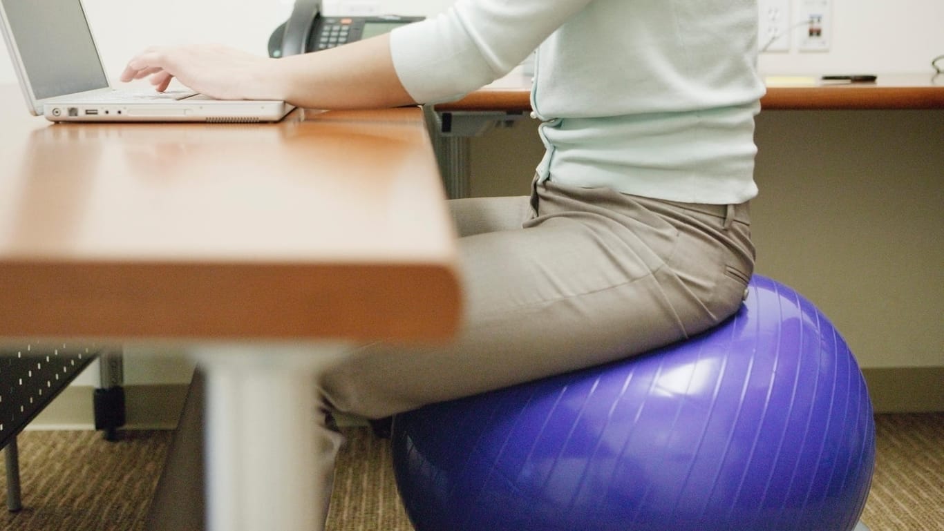 Eine Frau sitzt auf einem Gymnastikball: Ein verstellbarer Bürostuhl hat dem Ball gegenüber mehr Vort- als Nachteile.