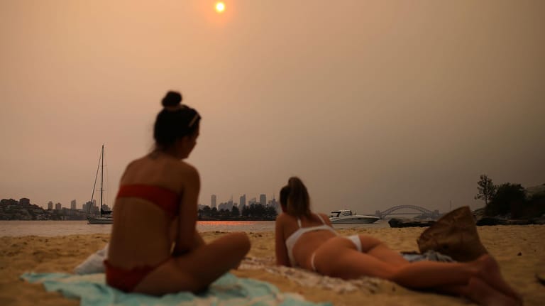 Strandbesucher betrachten im Smog die Skyline von Sydney. Der wochenlange Qualm stammt von den verheerenden Buschfeuern, die durch die klimabedingten Dürren begünstigt werden.