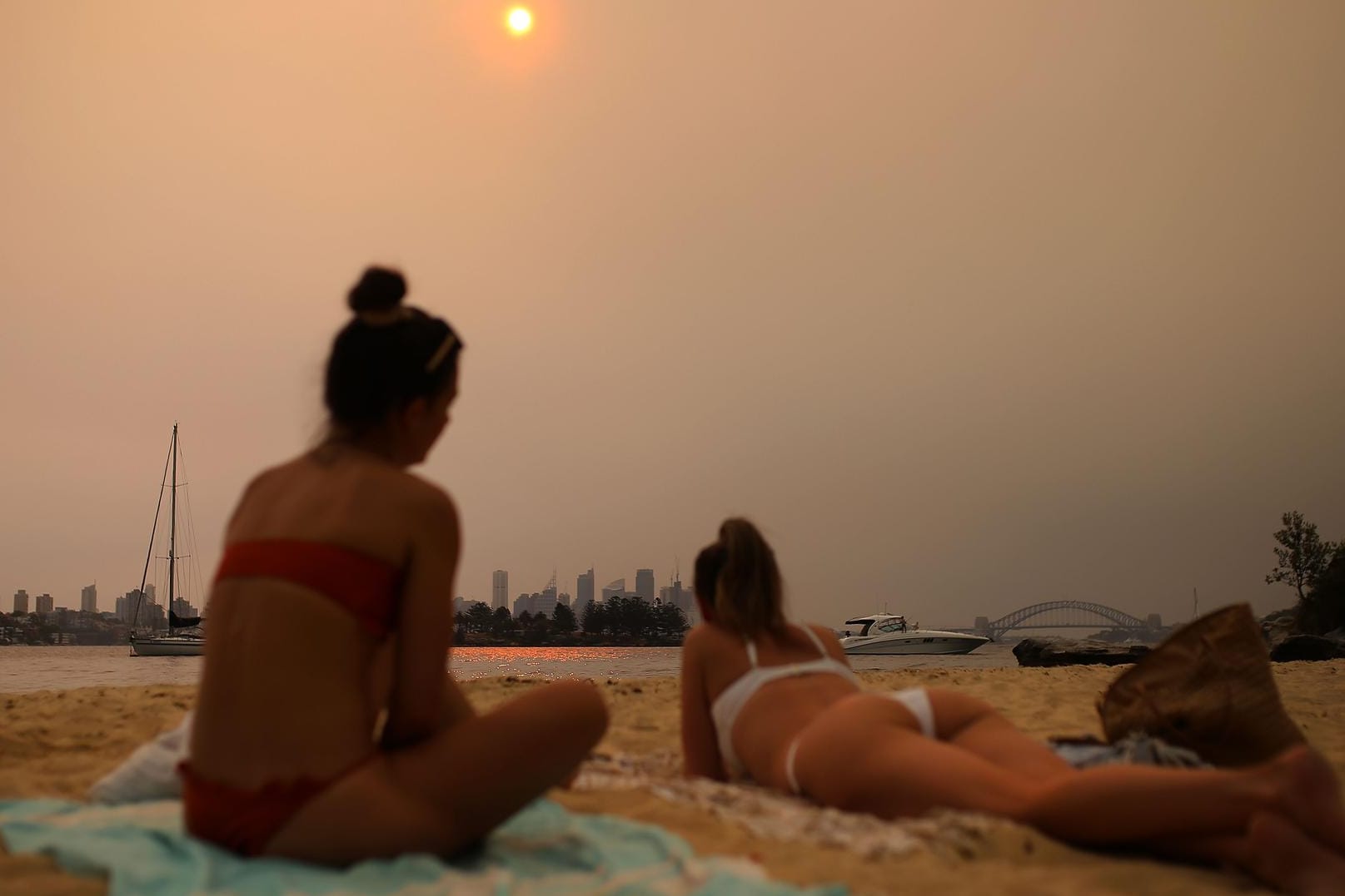 Strandbesucher betrachten im Smog die Skyline von Sydney. Der wochenlange Qualm stammt von den verheerenden Buschfeuern, die durch die klimabedingten Dürren begünstigt werden.