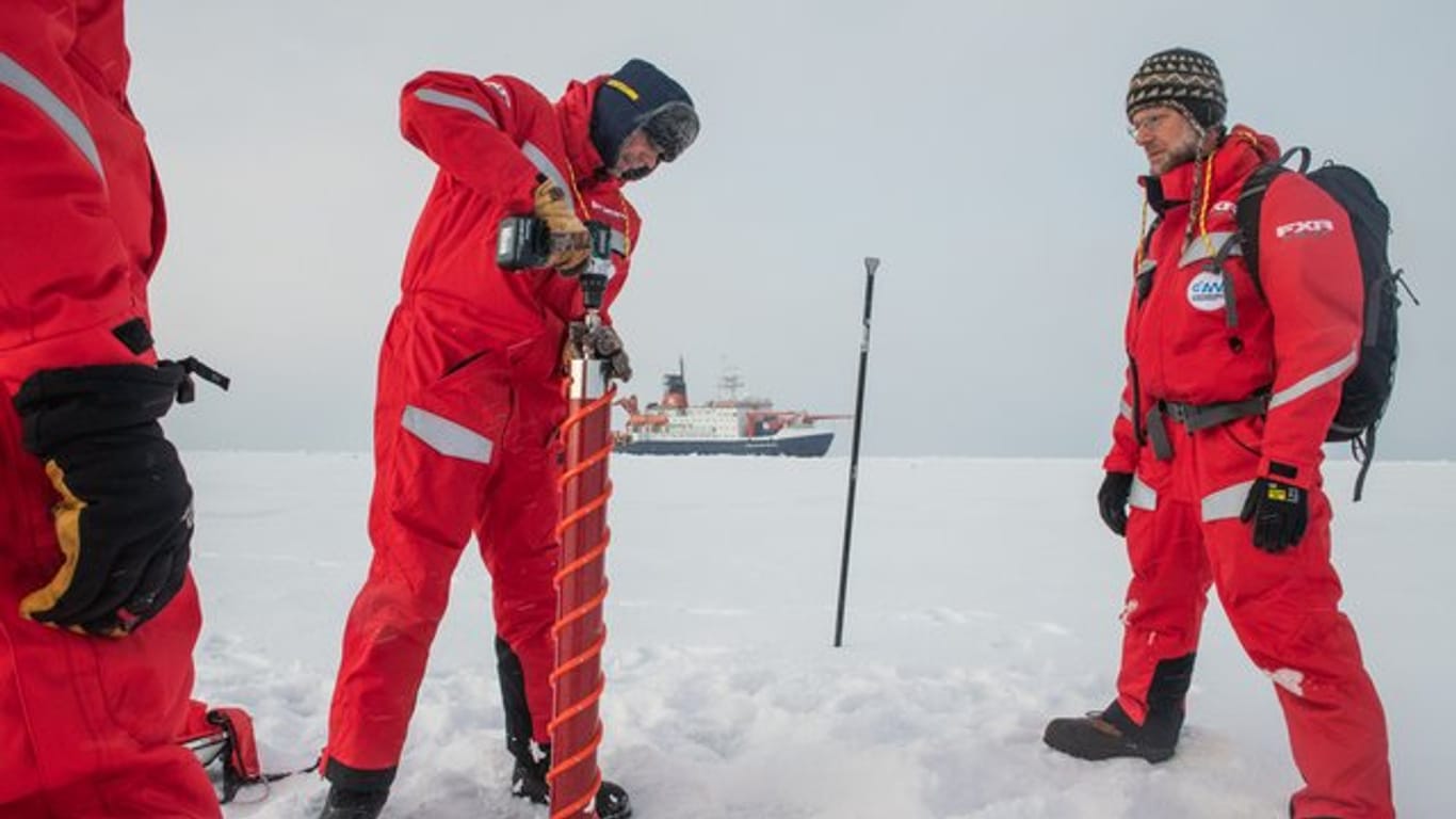 In Sichtweite des Forschungseisbrechers Polarstern untersuchen Wissenschaftler eine Eisscholle.