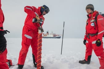 In Sichtweite des Forschungseisbrechers Polarstern untersuchen Wissenschaftler eine Eisscholle.