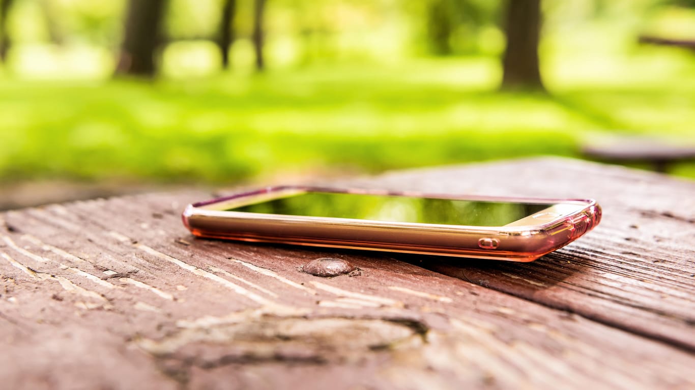 Ein Smartphone liegt vergessen auf einer Parkbank: Die teuren Handys rutschen gerne mal aus der Hosentasche.