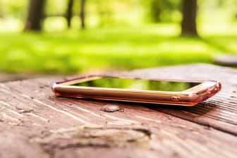 Ein Smartphone liegt vergessen auf einer Parkbank: Die teuren Handys rutschen gerne mal aus der Hosentasche.