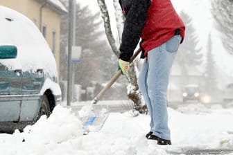 Ein Mann schippt Schnee: Der Grundstückseigentümer ist dafür verantwortlich, dass der angrenzende öffentliche Gehwege schneefrei ist. Doch er kann diese Pflicht auch auf die Mieter übertragen.