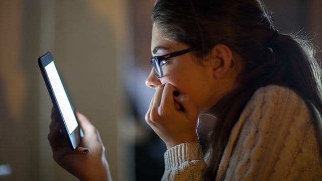 Eine junge Frau liest ein E-Book auf einem digitalen Lesegerät.