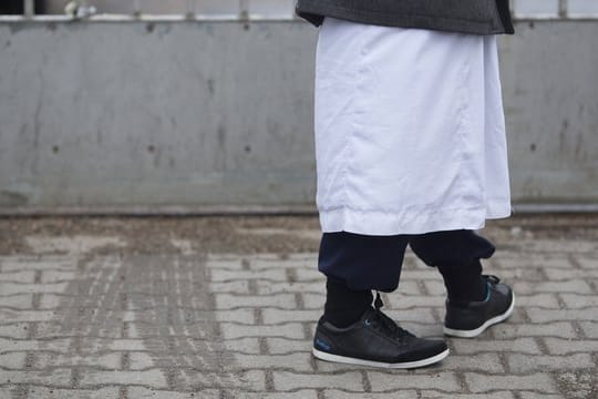Ein Mann in traditioneller Bekleidung steht vor einem Versammlungsort von Salafisten.