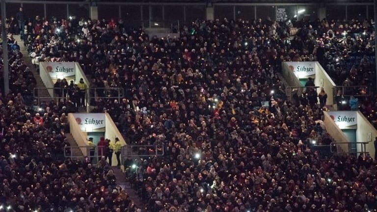 Menschen stehen zum gemeinsamen Singen im Ostseestadion