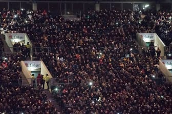 Menschen stehen zum gemeinsamen Singen im Ostseestadion