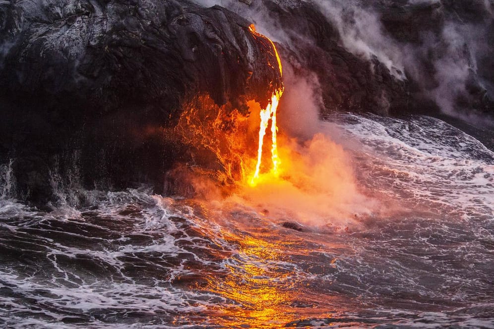 Heiße Lava ergießt sich ins Meer: Vor Milliarden Jahren war die Erde erst eine Gluthölle, dann ein Ozean. Die Urform allen Lebens entstand in Dunkelheit, Gas und Hitze – Luca. (Symbolfoto)