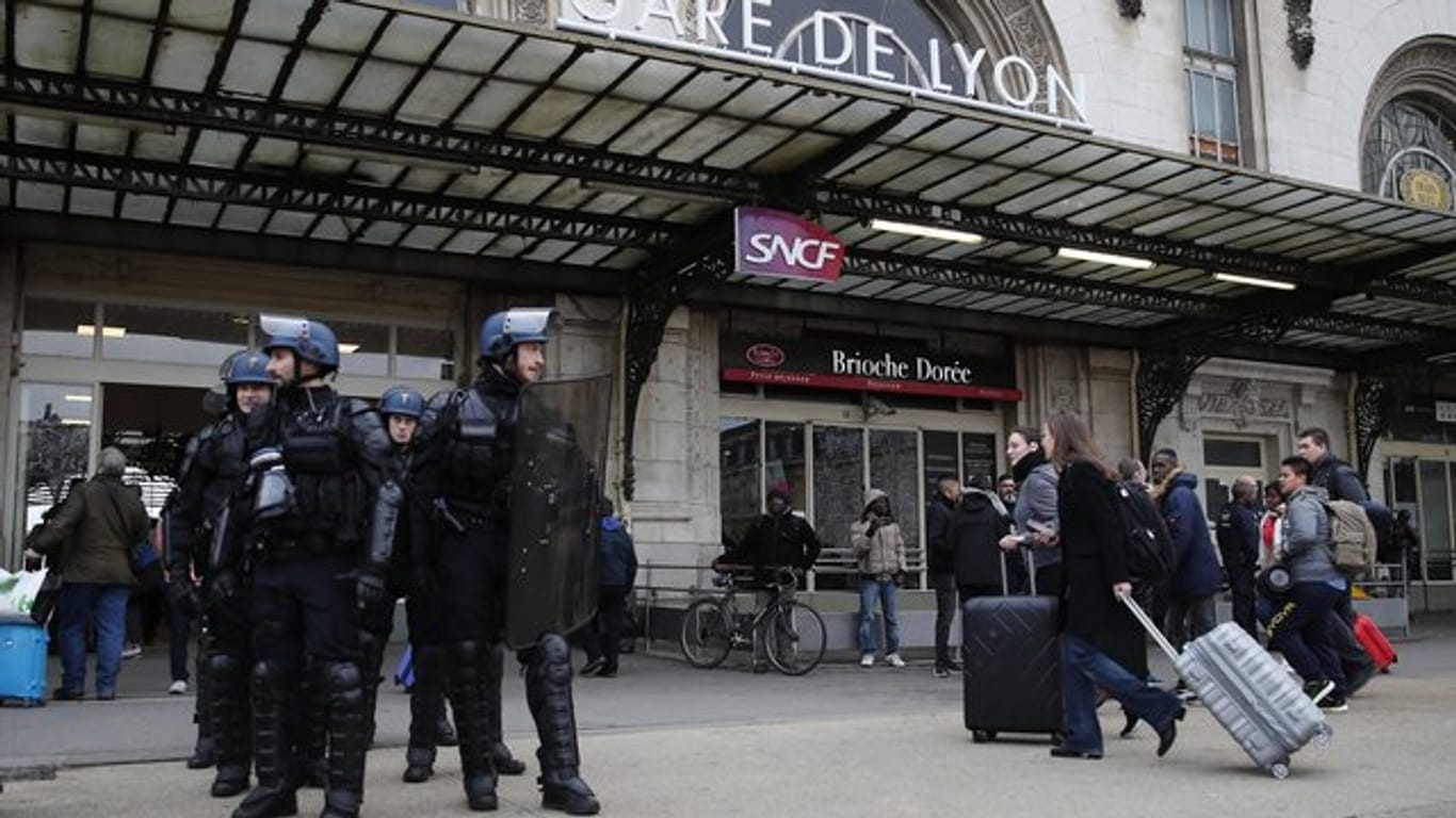 Reisende am Gare de Lyon, der während einer Demonstration der streikenden Eisenbahner von Polizisten bewacht wird.