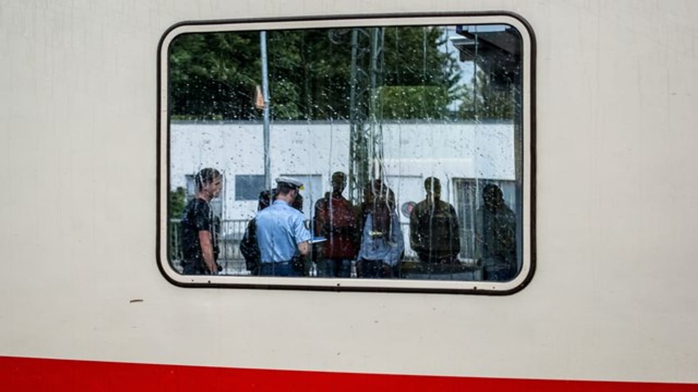 Zwei Bundespolizisten nehmen auf einem Bahnhof in Bayern die Personalien von im Zug aufgegriffenen Flüchtlingen auf.