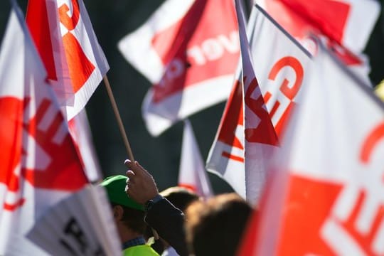 Teilnehmer eines Warnstreiks im öffentlichen Dienst schwenken Gewerkschaftsfahnen von GEW und Verdi.