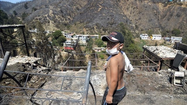 Ein Kind steht vor einem vom Feuer betroffenen Hügel in Valparaiso. Ein Kind steht vor einem vom Feuer betroffenen Hügel in Valparaiso.