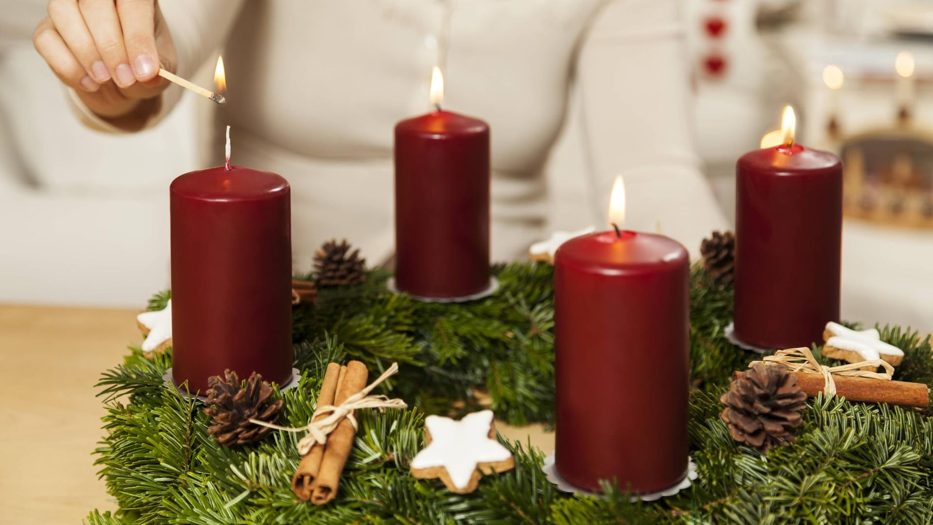 Eine Frau zündet die vierte Kerze eines Adventskranzes (Symbolbild): Ein ähnlicher Kranz hat in einer Wuppertaler Wohnung einen Brand verursacht. Eine Frau zündet die vierte Kerze eines Adventskranzes (Symbolbild): Ein ähnlicher Kranz hat in einer Wuppertaler Wohnung einen Brand verursacht.